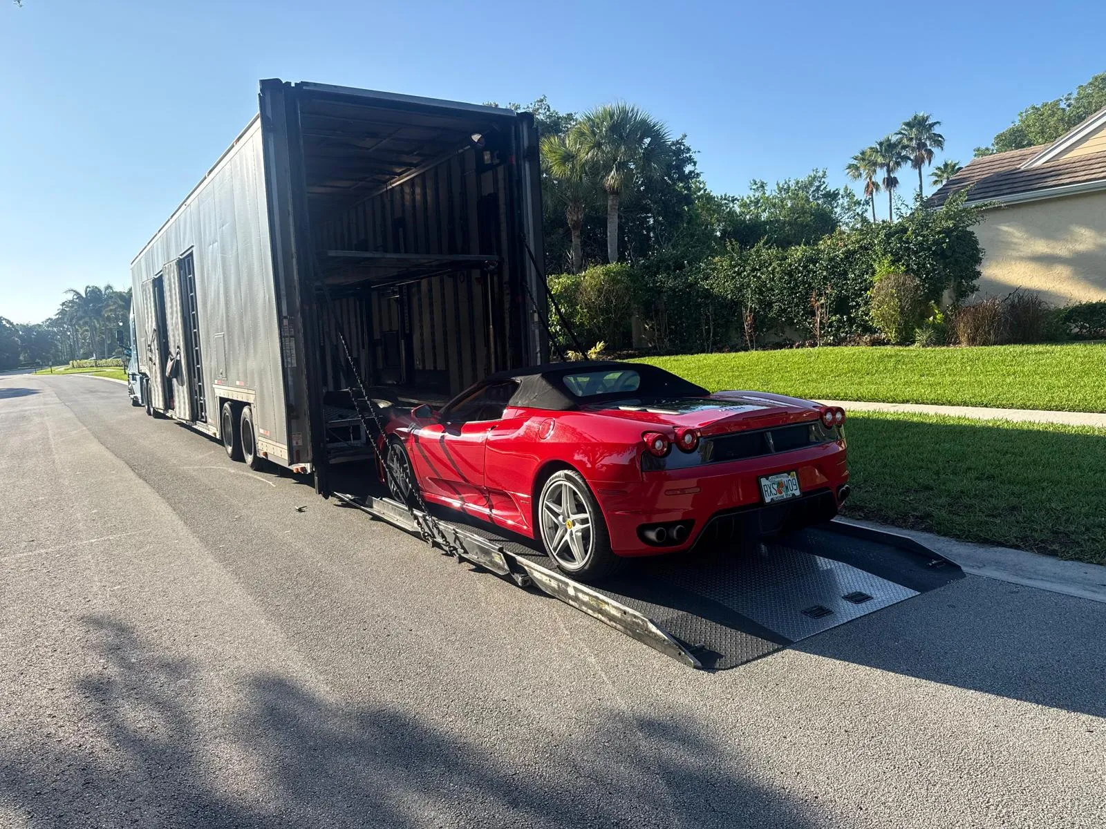 Red Ferrari Spider unloaded from enclosed trailer liftgate